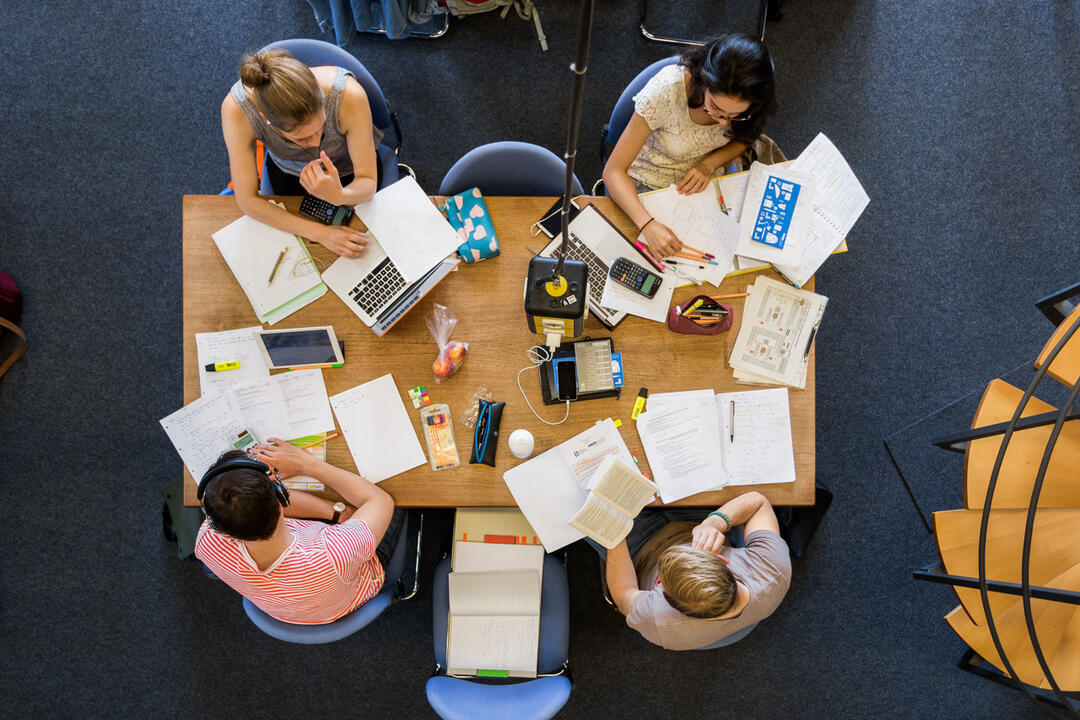 Studierende von oben an einem Tisch mit Büchern